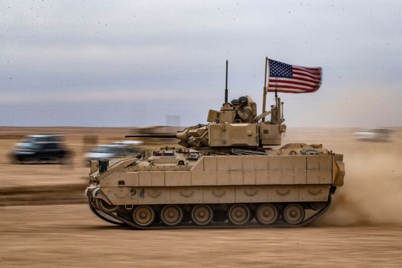 A tank roars across a desert.