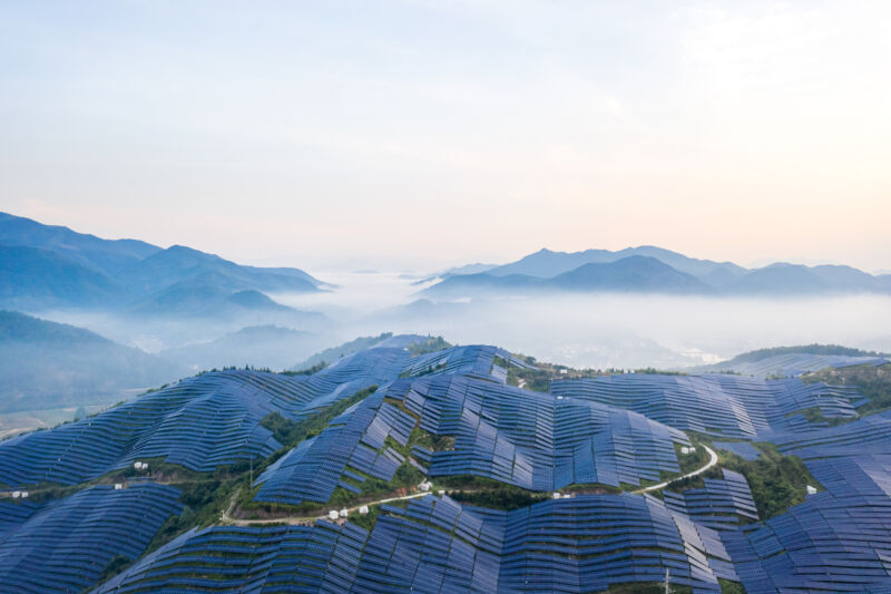 Solar panels cover a hillside.