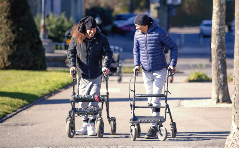 Image of two men standing behind walkers.