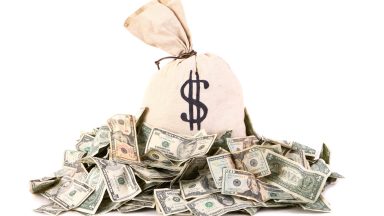 A bag of money surrounded by a pile of money.