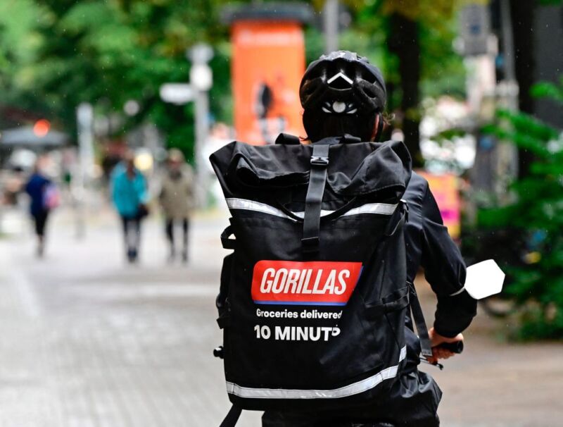 A bicycle courier of grocery delivery company "Gorillas" wears a backpack with the logo of the startup on his way to deliver purchases in Berlin.