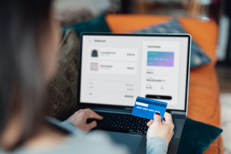 Fotografía de archivo de una mujer que usa una computadora portátil y una tarjeta de crédito para hacer una compra.