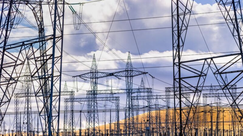 High-voltage electricity towers and power lines seen during daytime at a power substation.