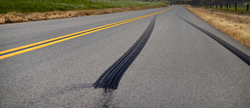 Image of a black tire skid mark down a road.