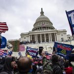 Crowds carrying pro-Trump flags attack a domed neoclassical building