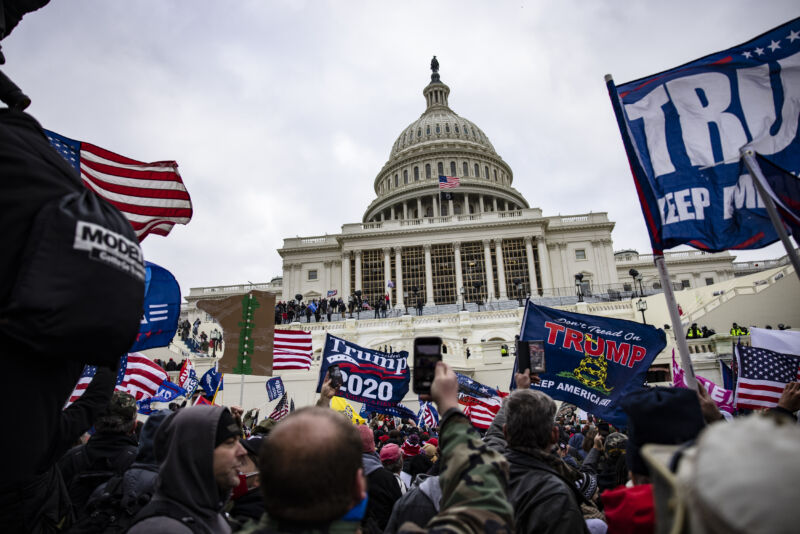 Crowds carrying pro-Trump flags attack a domed neoclassical building