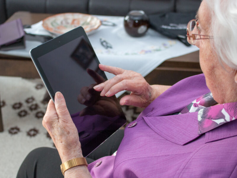 A silver-haired woman uses a tablet computer.