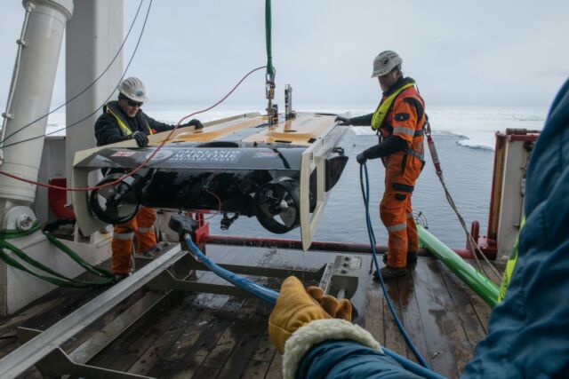 Crew members of the Endurance22 expedition retrieve an underwater drone after a search.