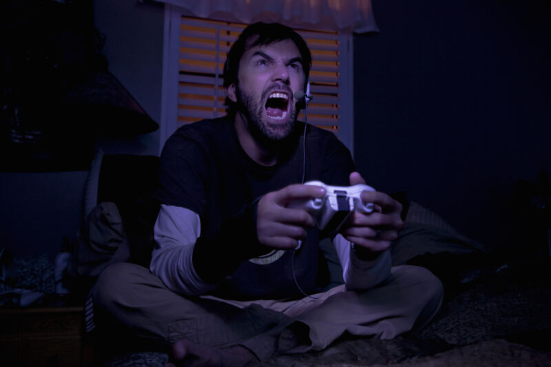 Stock photo of angry man angrily playing video games.