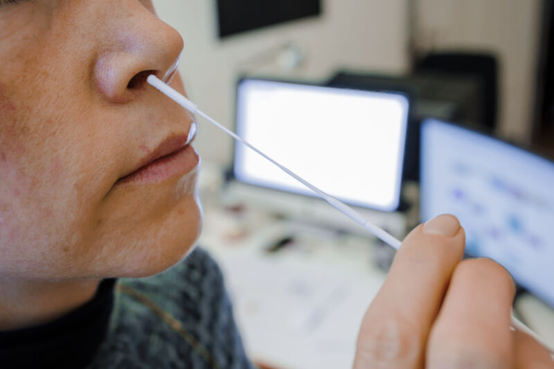 A woman holds a nasal swab for a COVID-19 antigen rapid test in front of her desk on January 5 in Berlin.