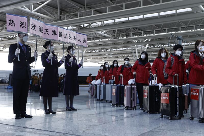 Train attendants holding signs welcome a medical team from Tianjin at Shanghai Hongqiao Railway Station on April 3, 2022 in Tianjin, China. A team of medical workers from Tianjin arrived in Shanghai on Sunday to support the city's fight against COVID-19 epidemic.
