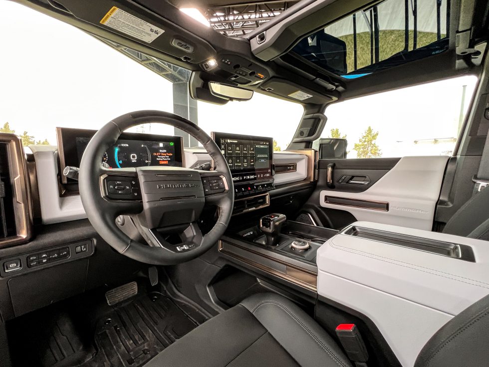 El interior del Hummer EV tiene un estilo audaz, con detalles resistentes en cosas como las pantallas de visualización.  Hay una palanca de transmisión convencional y grandes botones físicos para los controles de clima y para cambiar los modos de manejo.  Y los paneles del techo son desmontables.