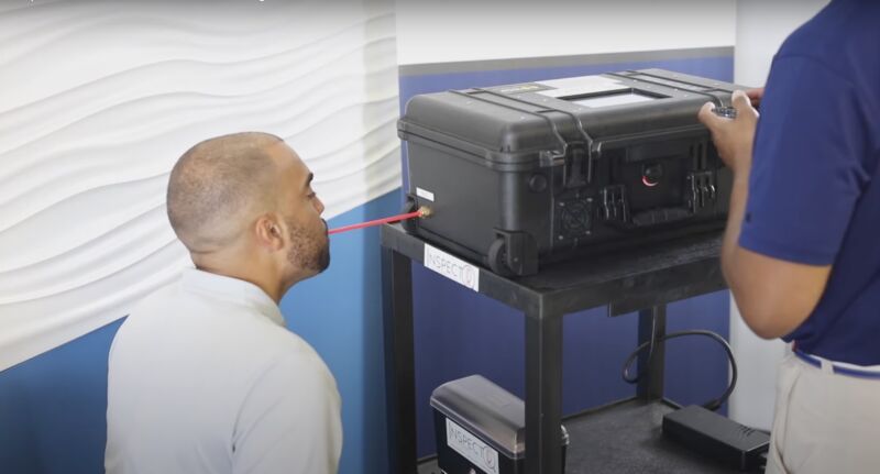 Man providing a sample into the InspectIR COVID-19 Breathalyzer.