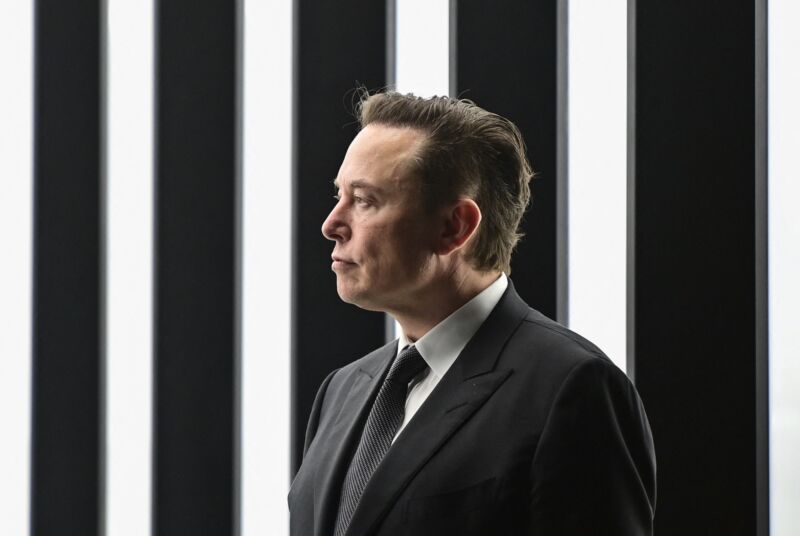 Elon Musk con traje durante un evento en una fábrica de Tesla.