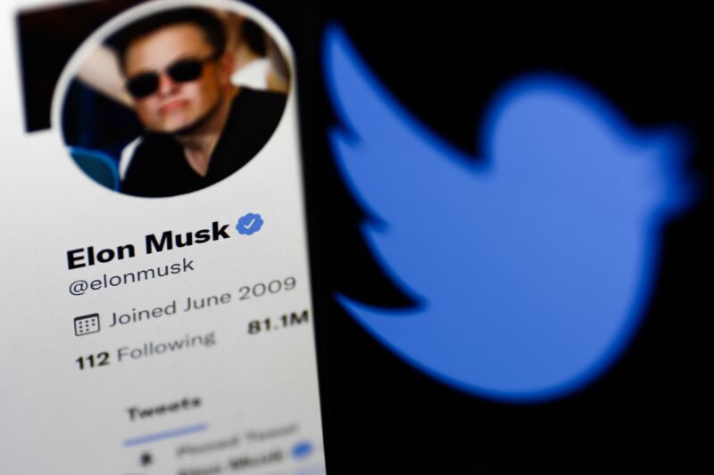 Elon Musk's Twitter profile displayed on a computer screen juxtaposed next to a Twitter logo displayed on a phone screen