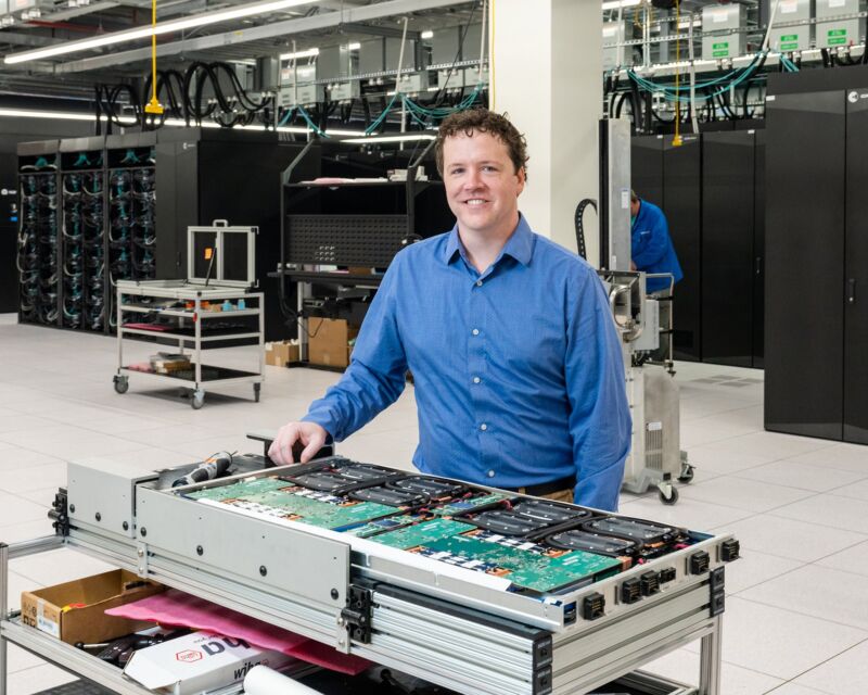 A systems engineer stands in a large room containing the Frontier supercomputer.