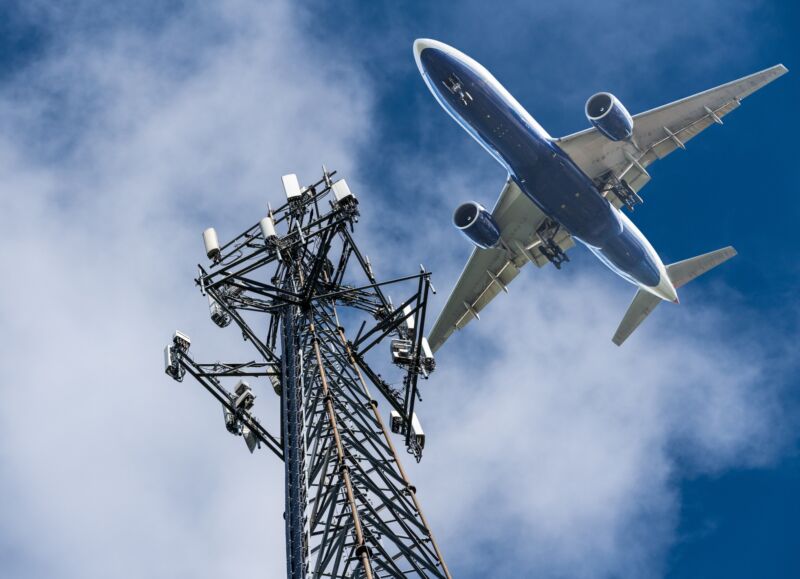 An airplane flying past a cell tower.