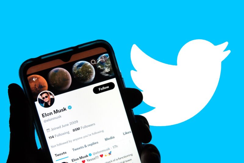 In this photo illustration, Elon Musk's twitter account is displayed on a smartphone in front of a background with the twitter logo.