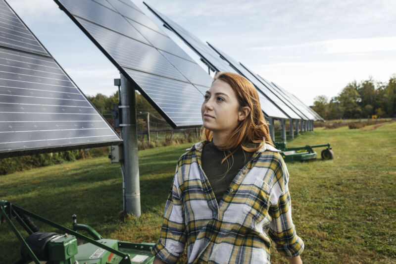 Image of a woman standing in front of solar panels.