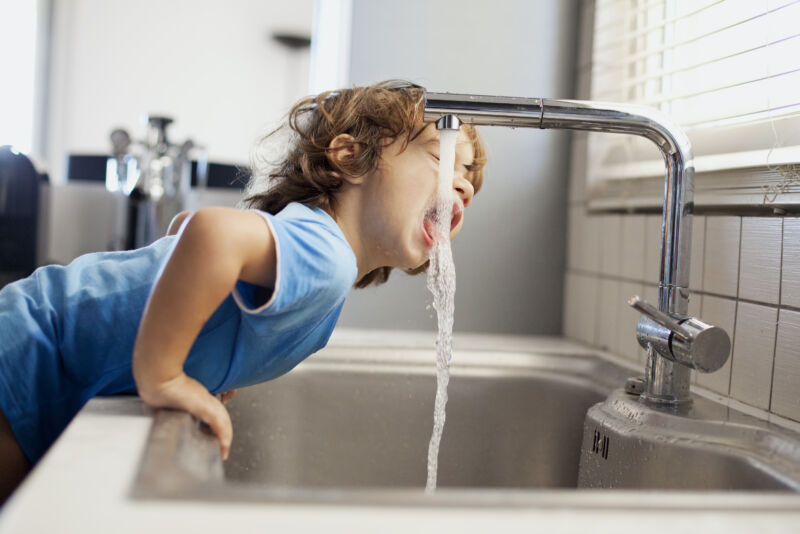 Image of a child drinking from a tap.