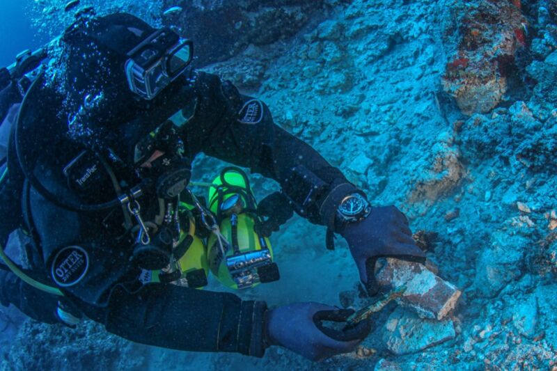A diver through the Return to Antikythera Project carefully excavates an artifact.