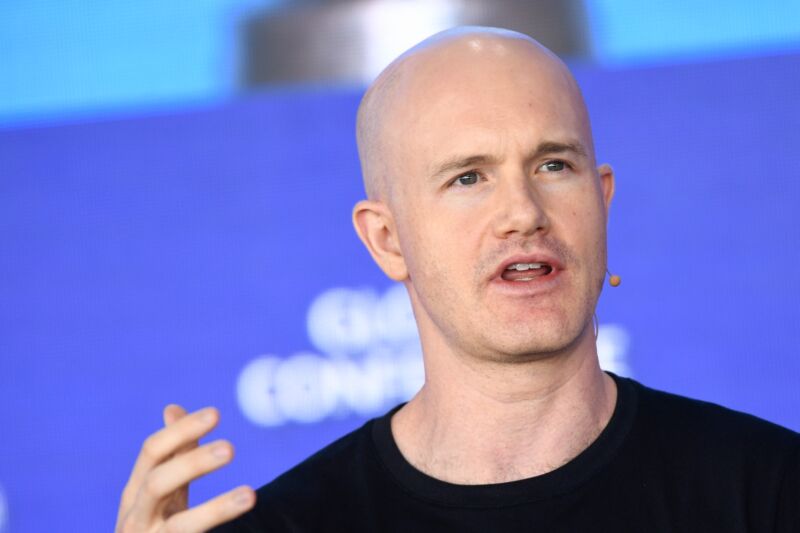 El CEO de Coinbase, Brian Armstrong, hablando en una conferencia y gesticulando con la mano.