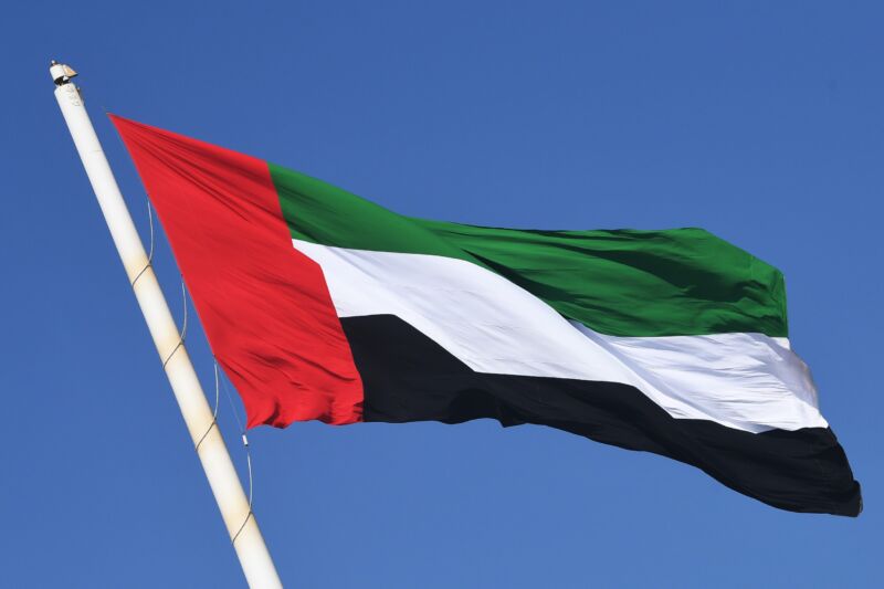 The United Arab Emirates flag blowing in the wind on a flagpole.