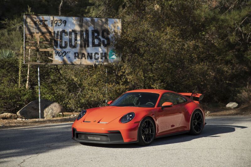 An orange Porsche 911 GT3 next to the Newcombs ranch sign on the Angeles crest highway