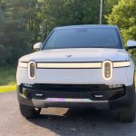 A white Rivian R1S in the late afternoon sun, seen head-on