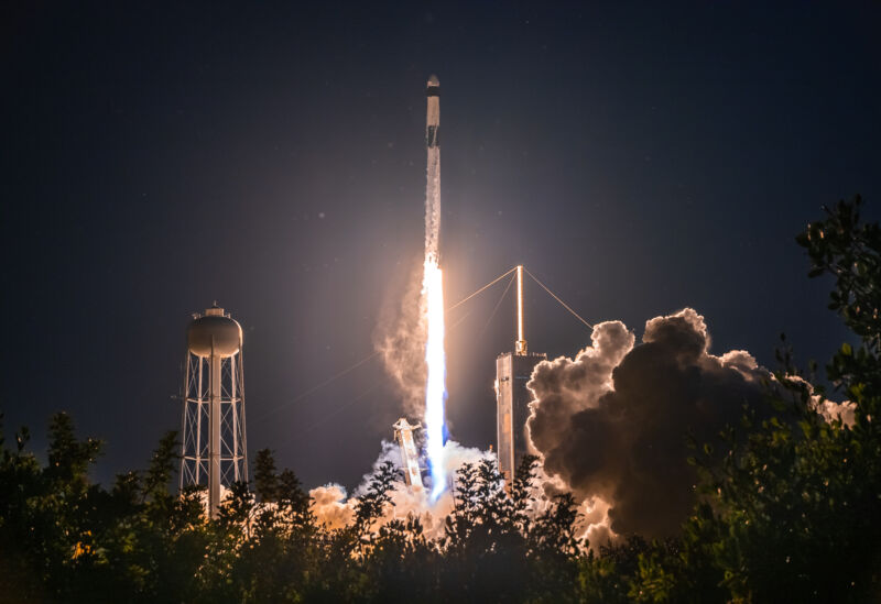 No Falcon 9, o CRS-25 decola na sexta-feira à noite.  Se você aumentar o zoom, poderá ver mosquitos espalhados por toda a imagem, iluminados pelo escapamento do foguete ao fundo.