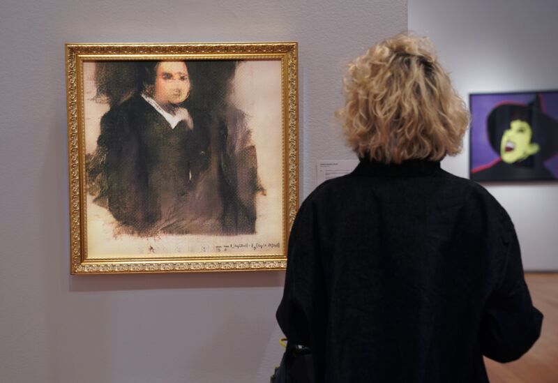 A woman looks at a work of art created by an algorithm by French collective named OBVIOUS, which produces art using artificial intelligence, titled <em>Portrait of Edmond de Belamy</em> at Christie's in New York on October 22, 2018. The piece sold for $432,500.