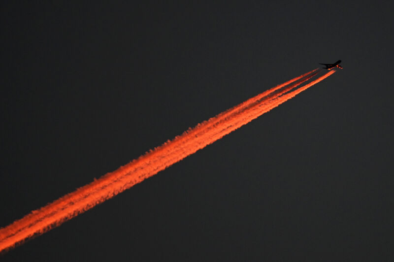 The evening sun colors the underside of the Boeing 747 and the following contrail red in Berlin in 2021. 