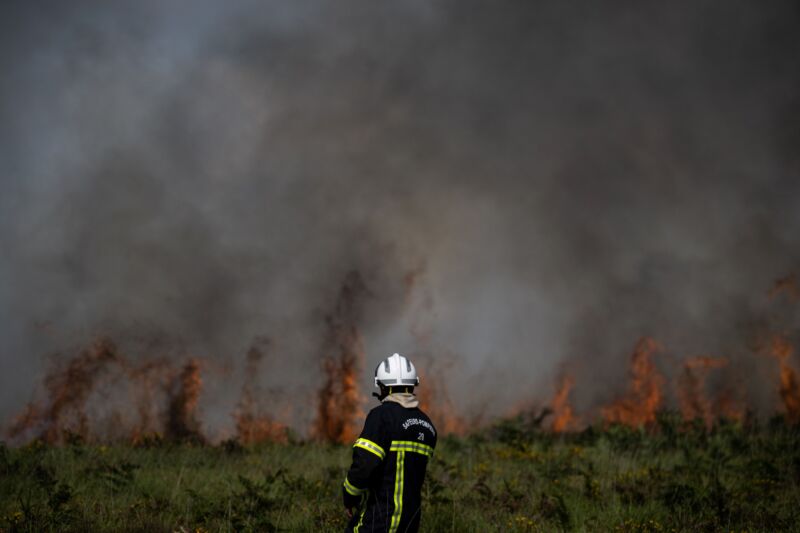 A firefighter stands by flames as a wildfire rages in the Monts d'Arree, near Brasparts, Brittany, on July 19, 2022. A heatwave fueling ferocious wildfires in Europe pushed temperatures in Britain over 40° Celsius (104° Fahrenheit) for the first time after regional heat records tumbled in France.