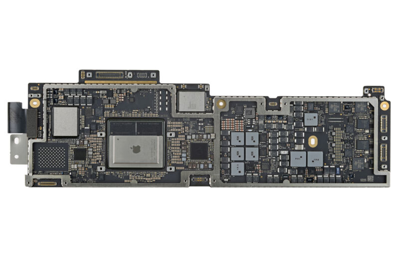 Papan logika M2 MacBook Air.  M2 adalah chip besar di kiri tengah dengan logo Apple tercetak di atasnya. 