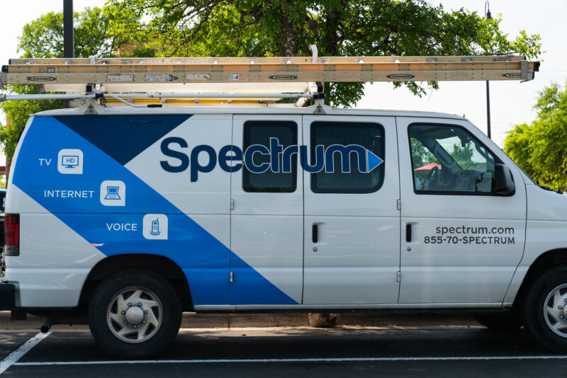 A parked van used by a Spectrum cable technician. The van has the Spectrum logo on its side and a ladder stowed on the roof.