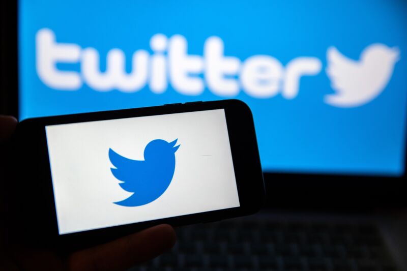 In this photo illustration, a Twitter logo is displayed on a smartphone screen and a laptop screen.