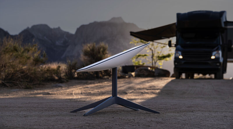 A Starlink satellite dish photographed on the ground, near a motorhome.