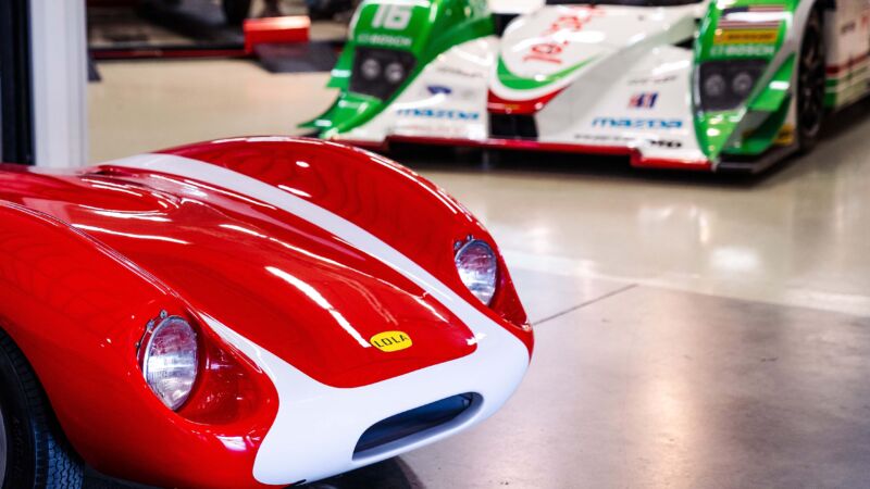The nose of a red Lola Mk1 in the foreground and a white and green Lola B12/60 in the background