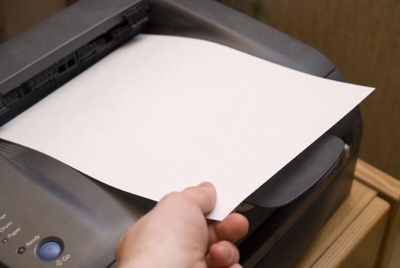 Someone touching a piece of paper that's sitting in a printer