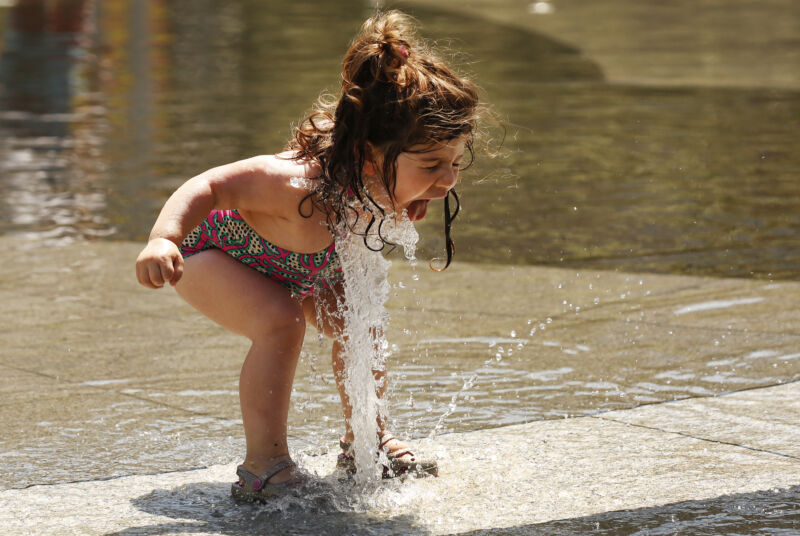 Un băiețel de doi ani se bucură să stropească cu apă într-un tampon de stropire în Los Angeles, pe 20 iunie 2022.