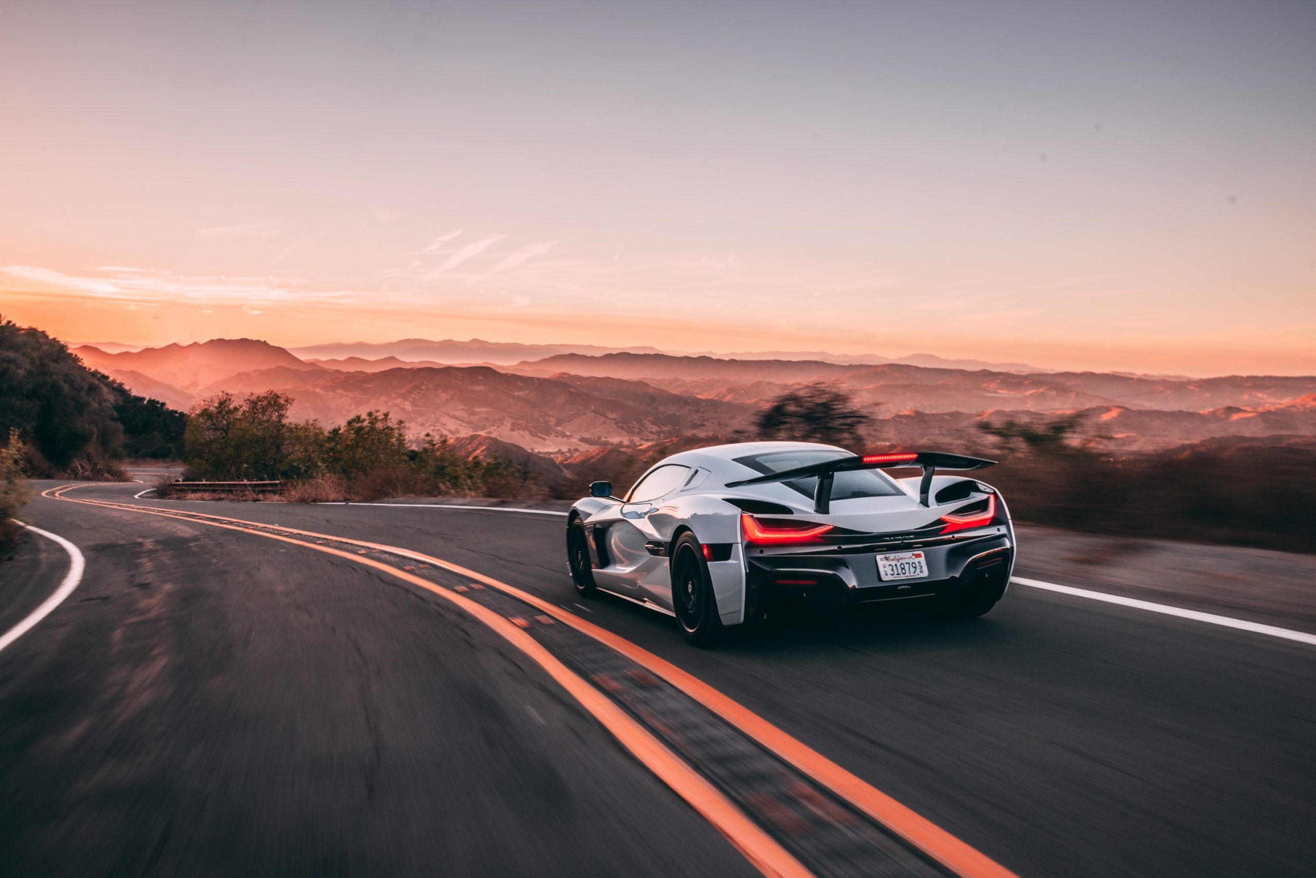 A white Rimac Nevera seen from behind on the road
