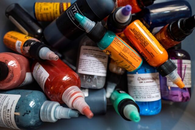 Flaschen mit farbiger Tinte stapeln sich in einer Kiste in einem Tattoo-Studio in Berlin.