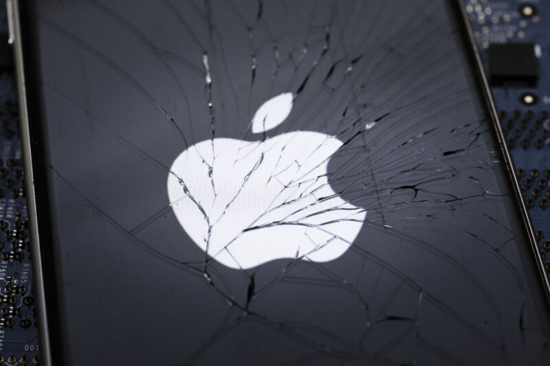 The Apple logo is displayed on a smartphone with splintered glass