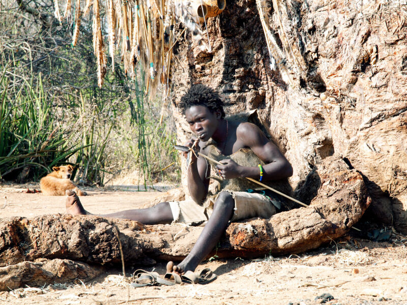 Un joven bosquimano hadza haciendo una flecha para un arco de caza. 