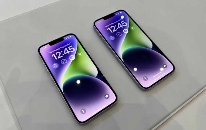 Two purple iPhones lying on a table. Both show a lock screen with some live widgets.