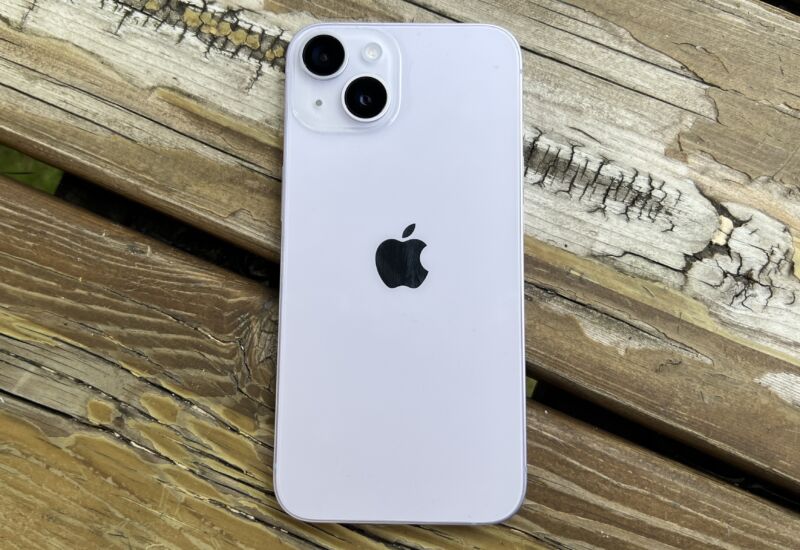 The back of an iPhone 14, lying on a wood table outdoors