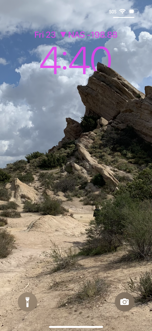 A rocky outcropping in a photo blocks part of the clock on the iPhone's lock screen