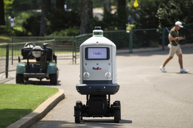 A Fedex delivery robot with a golf player in the background
