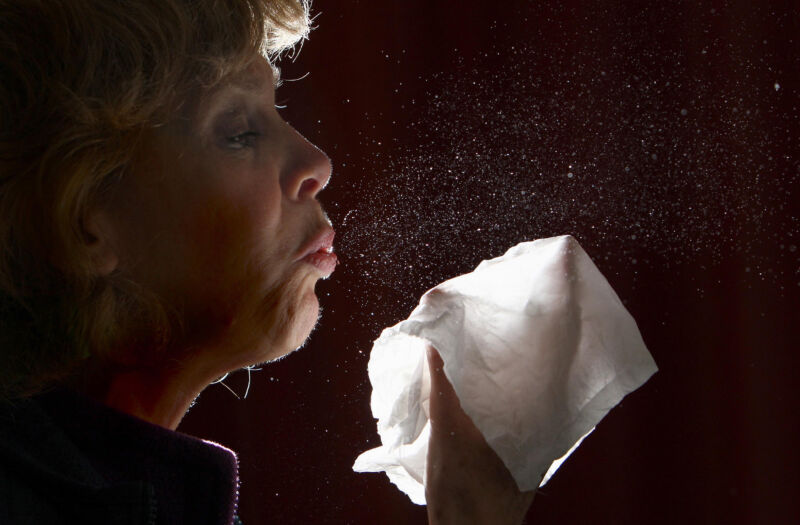 A close-up view of a woman sneezing. 