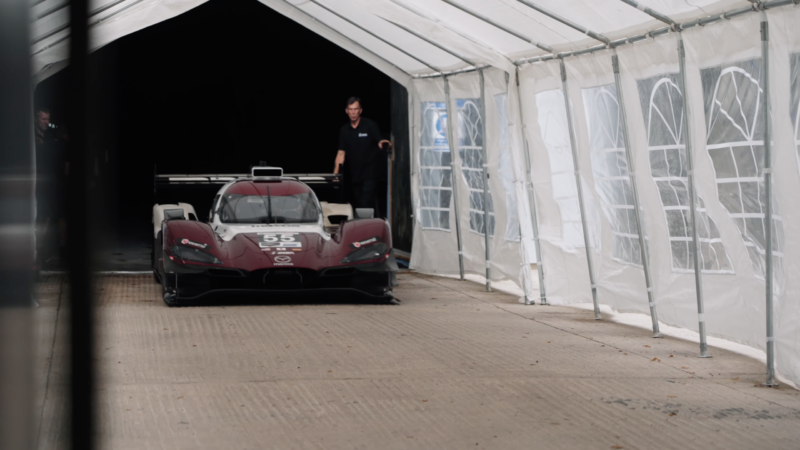A mazda racing prototype enters a white tent after leaving a tunnel